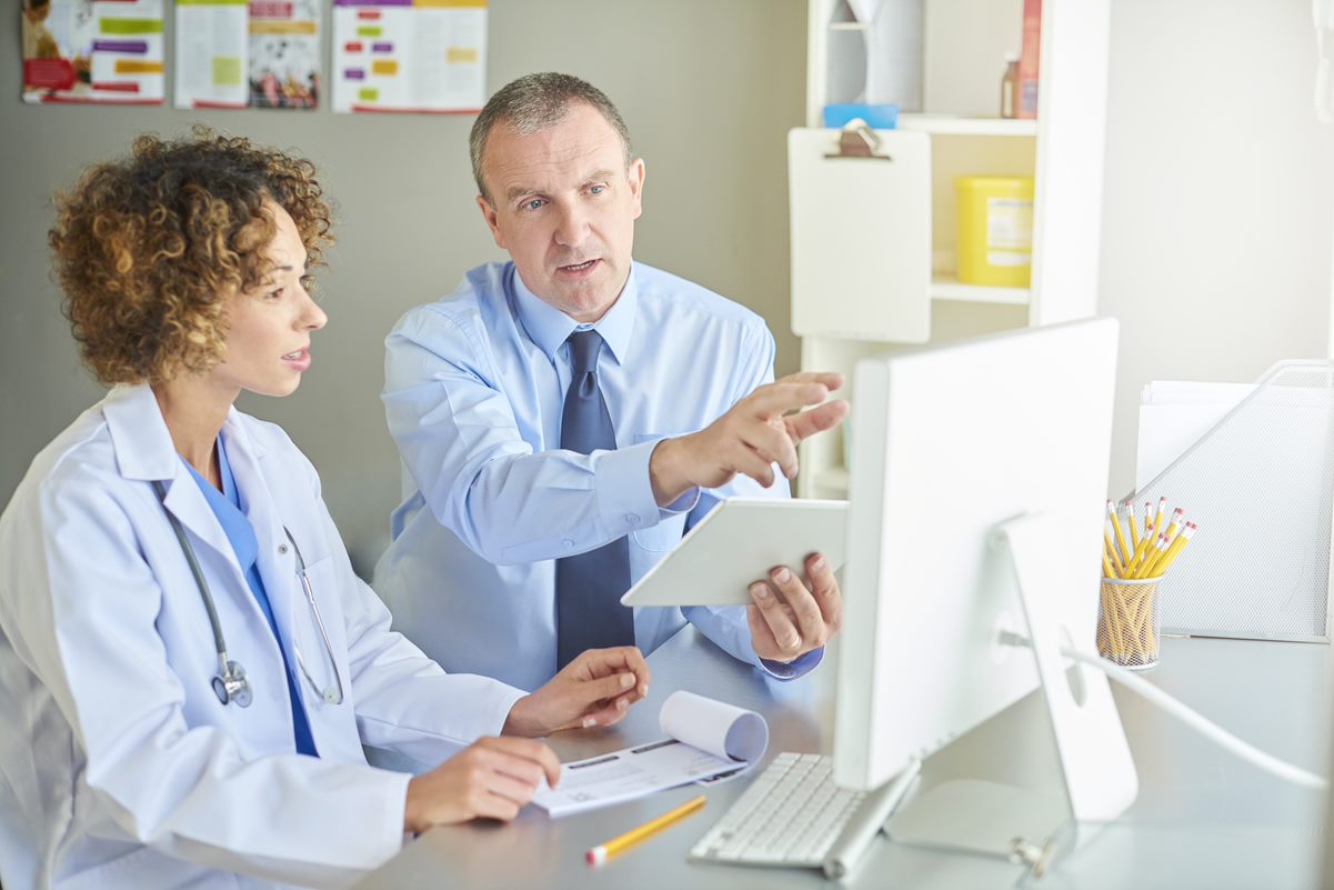 A male doctor is explaining to female doctor what is on the monitor. 