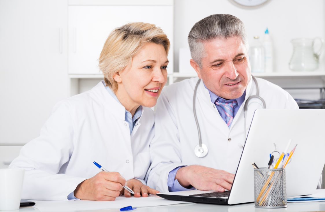 Two health care professional looking a computer monitor.