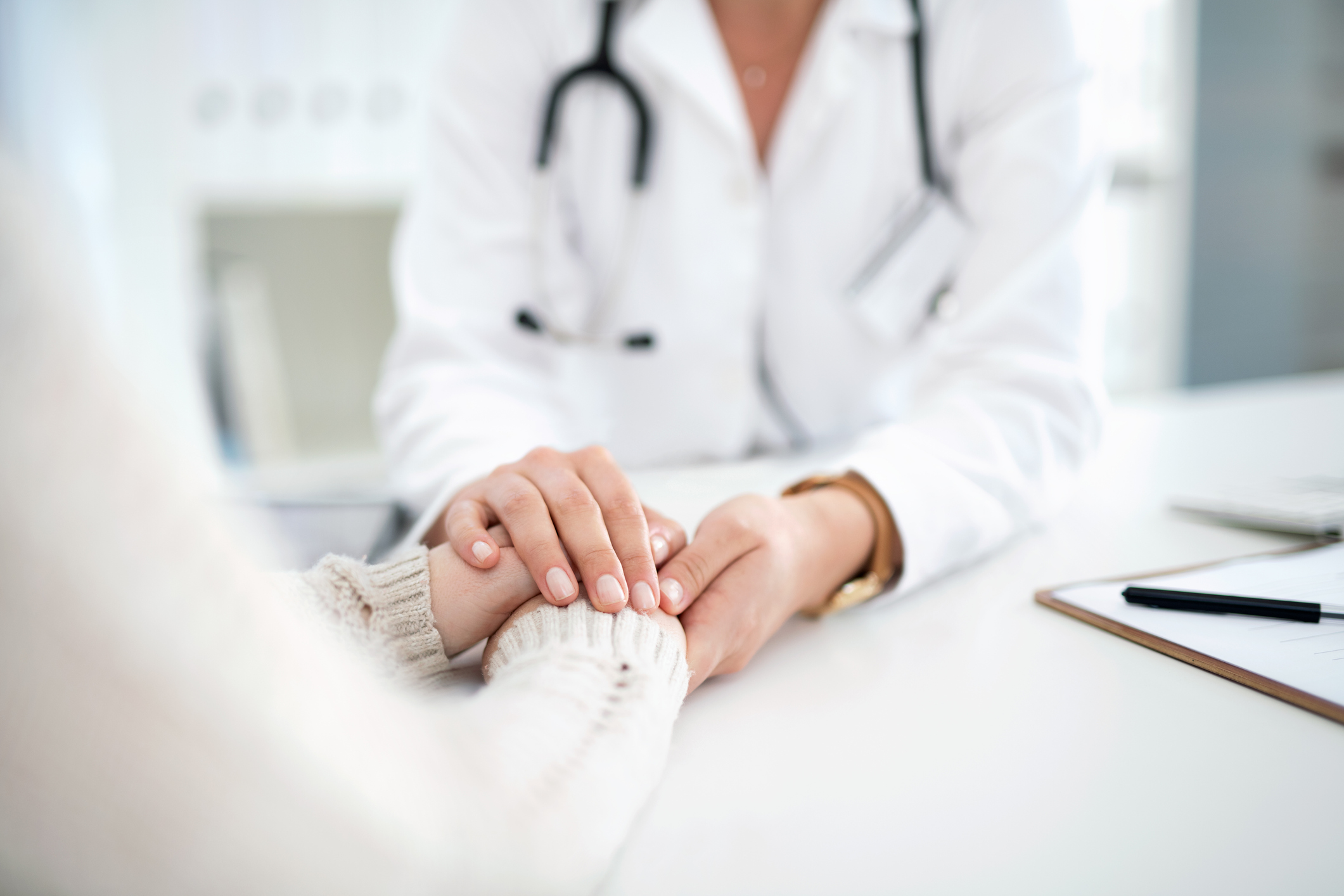 Neck down image of a doctor holding a persons hands.