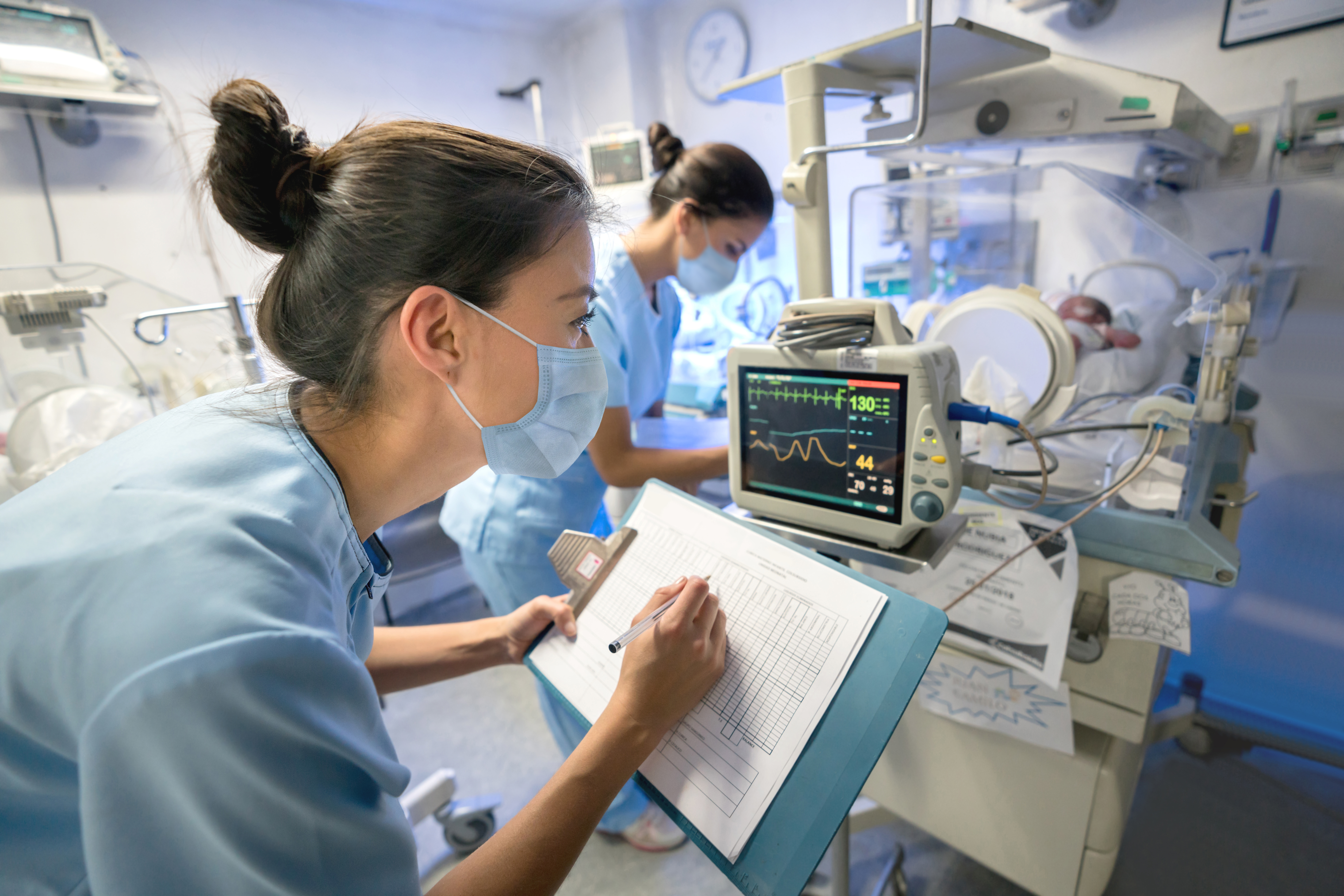 Nurse writing down stats from a monitor.