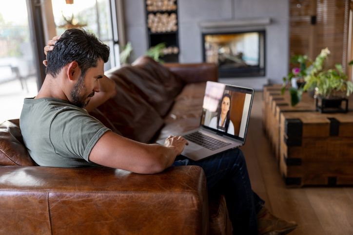 A male sitting on a couch working on laptop.