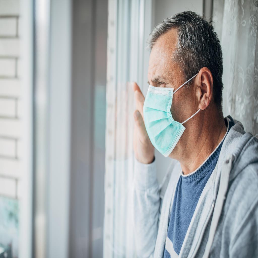 Man with a mask on starring out the window.