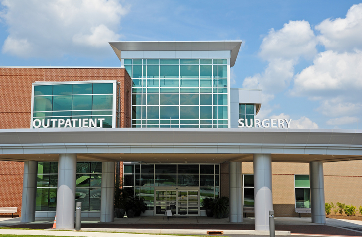 The outside of a medical building that has a "outpatient" sign on the left of the building and a "surgery" sign on the right.