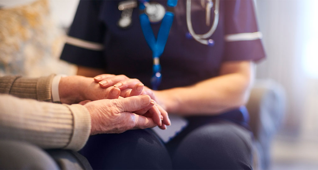 A nurse holds an elderly patient's hand