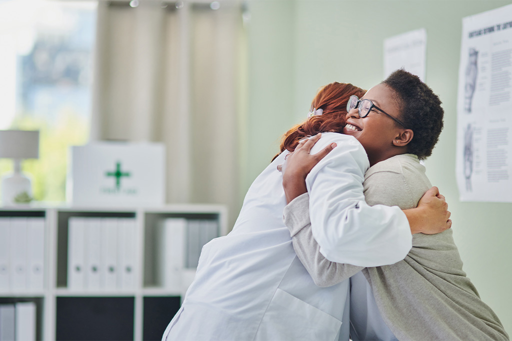 A patient hugs her doctor in an observation room