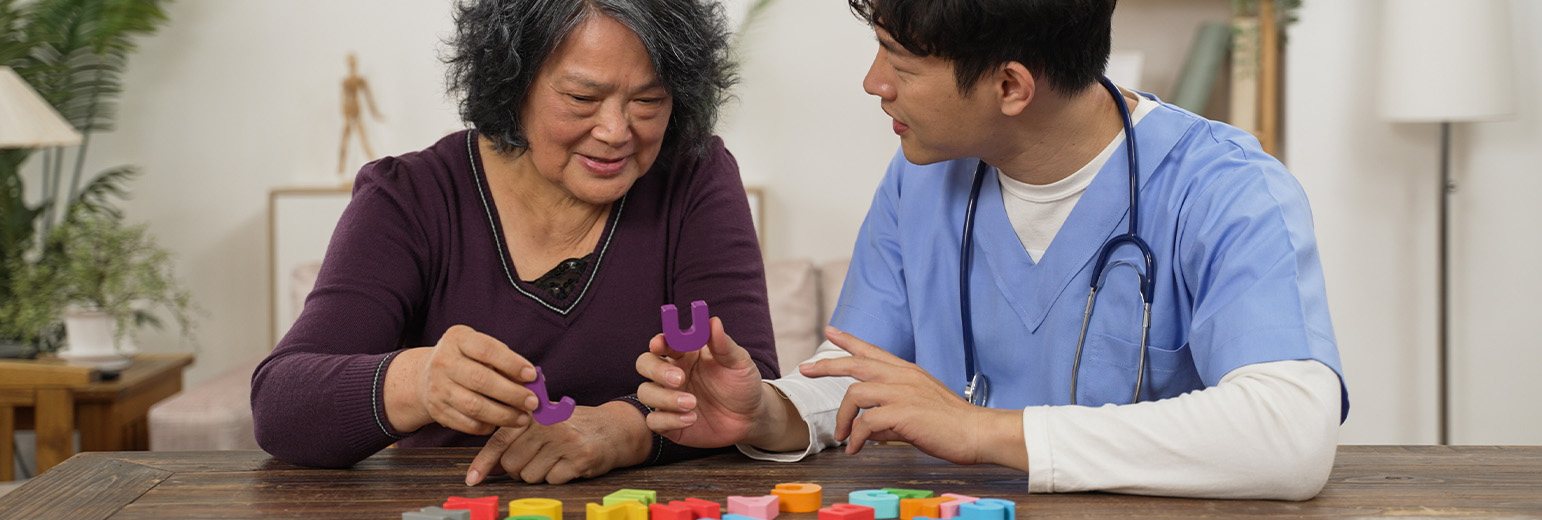 An elderly patient works on a puzzle with a nurse