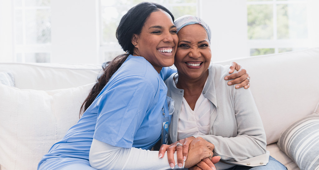 A nurse embraces a patient in her home