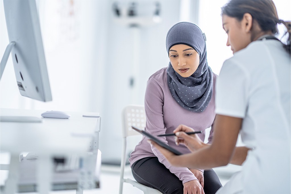 A nurse shares information on a tablet with a patient