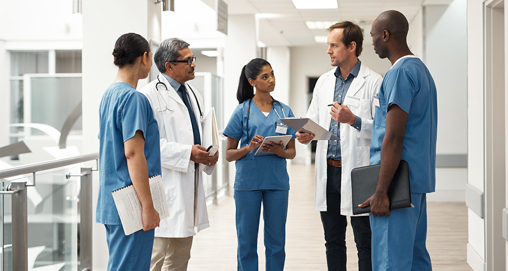 A team of doctors and nurses have a meeting in a hospital lobby