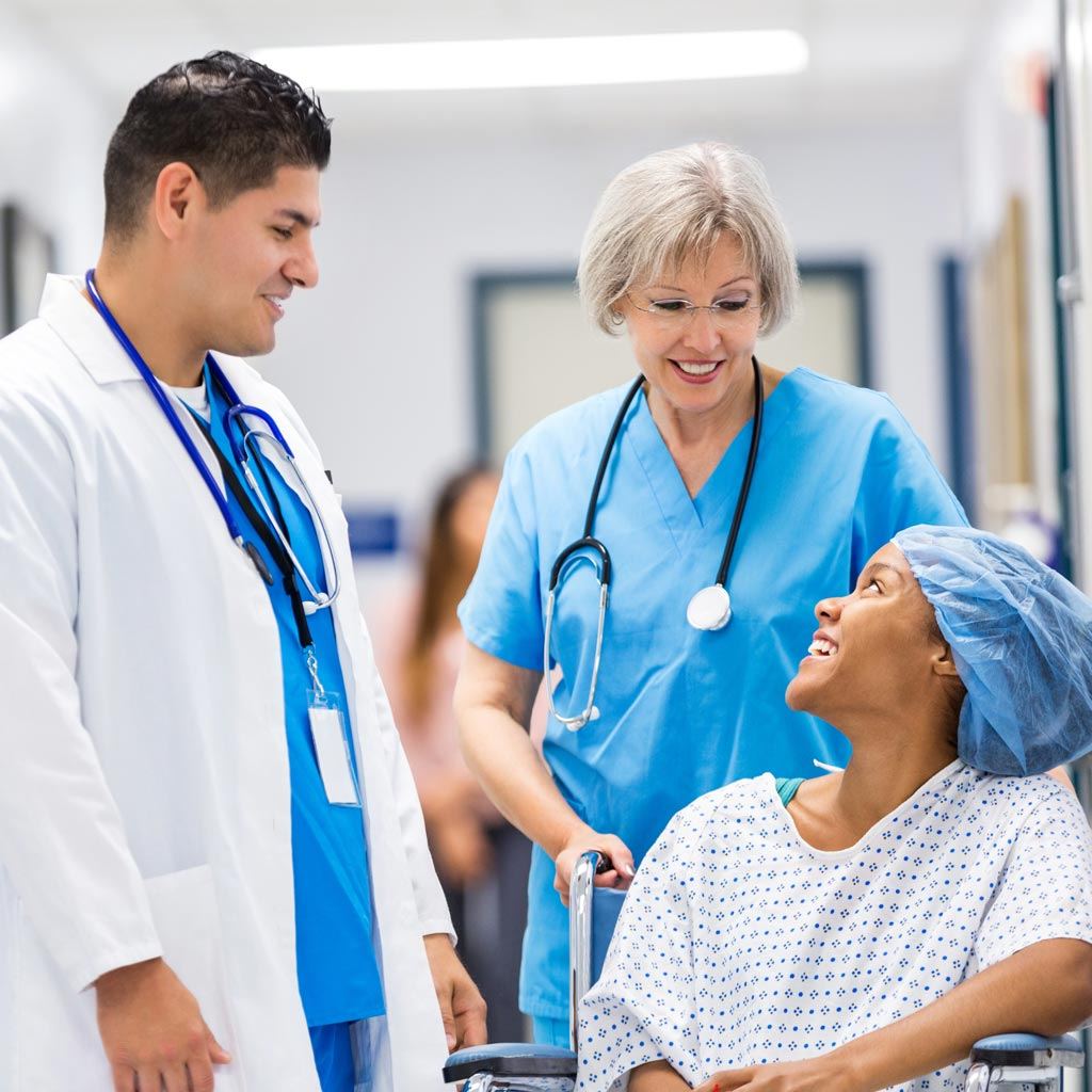 Nurse and doctor talking to happy hospital patient after surgery