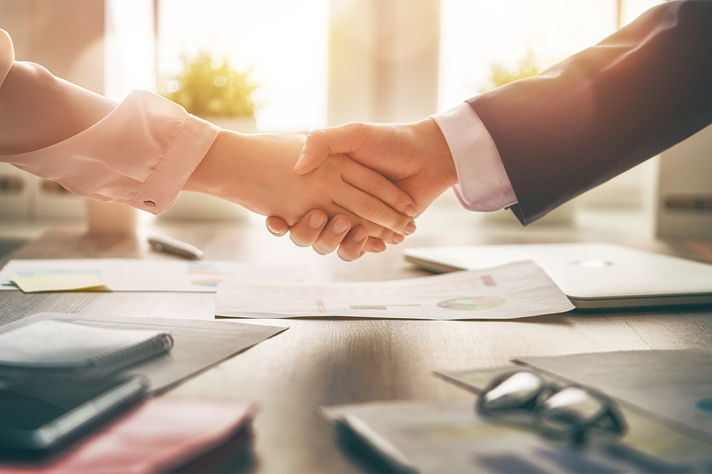 A close up of two individuals in professional attire shaking hands