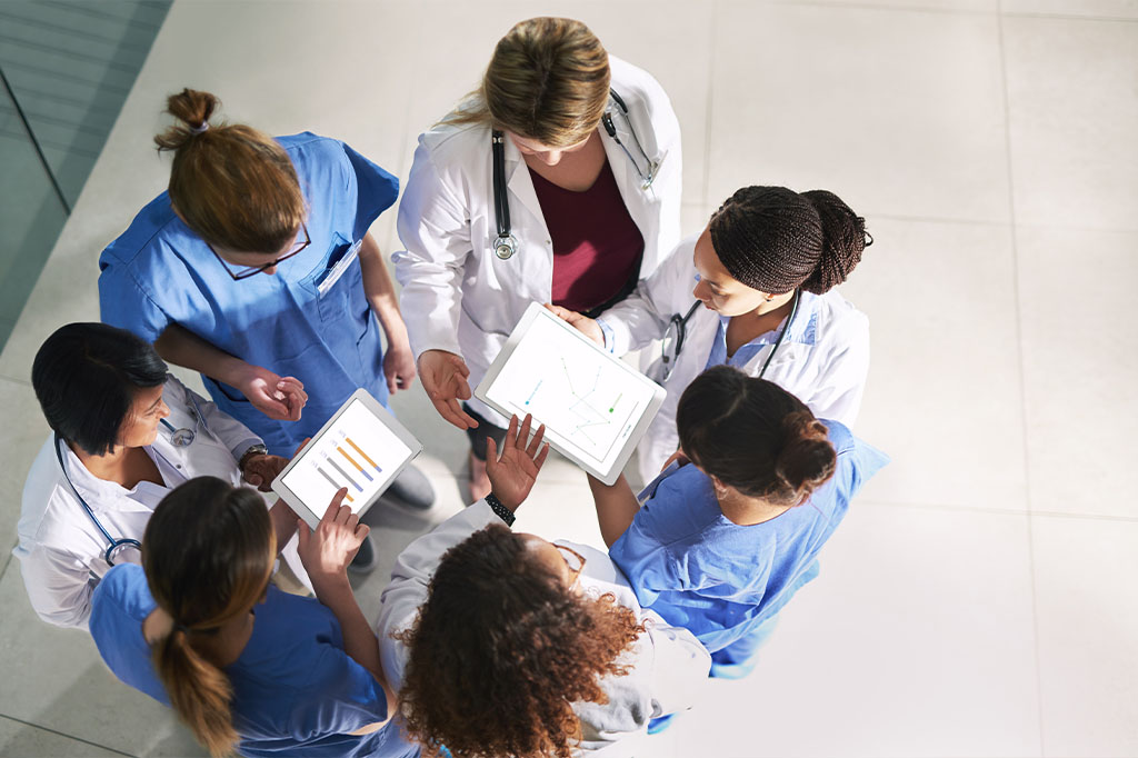 A team of doctors and nurses have a meeting in a hallway