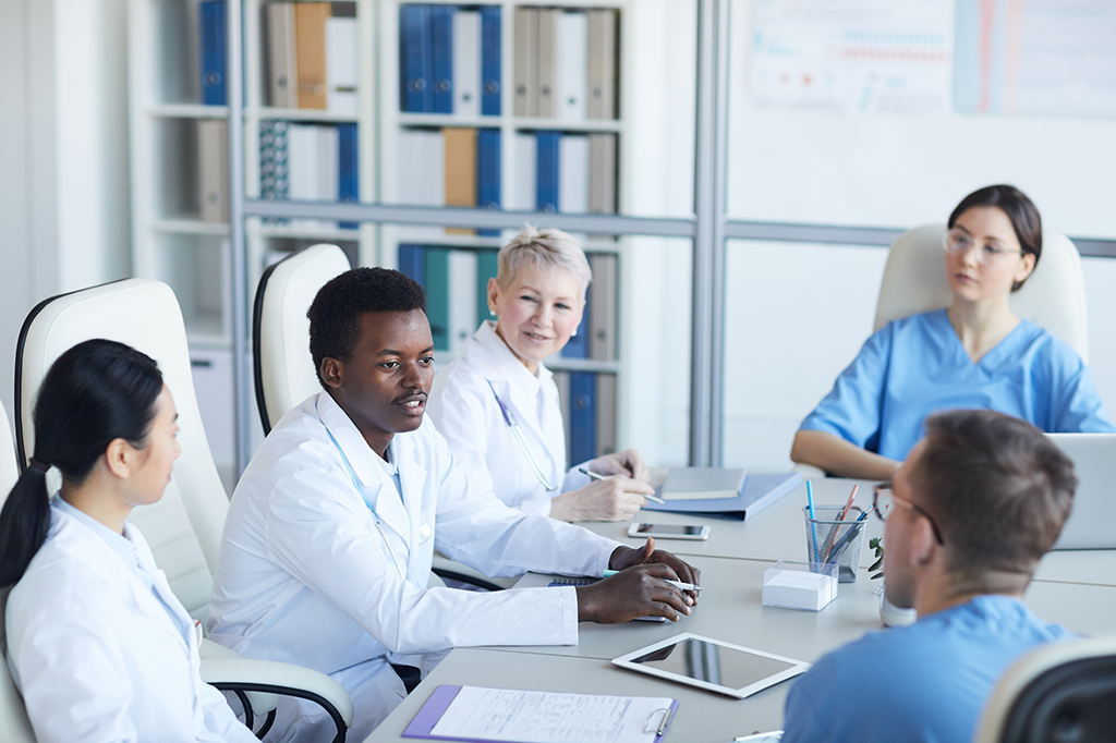 A group of medical professionals sit around a table talking.