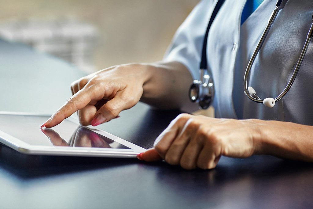 Close up image of a doctor's hands using a tablet.