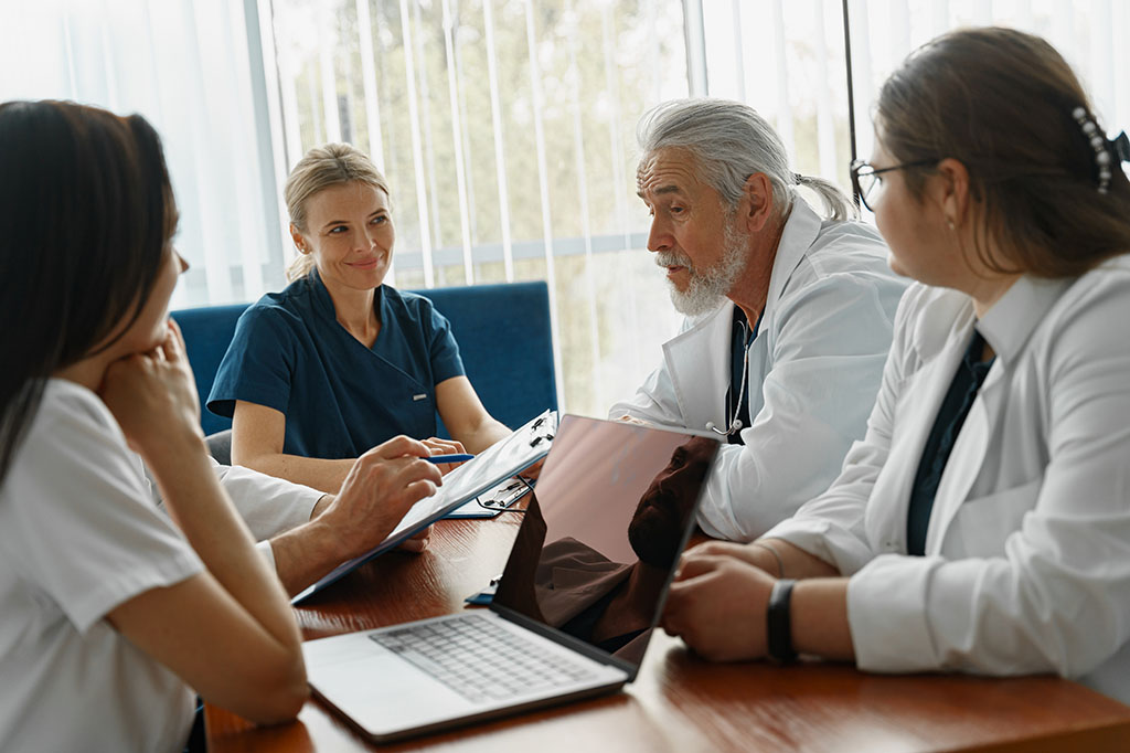 Four medical professionals sit at a meeting table.