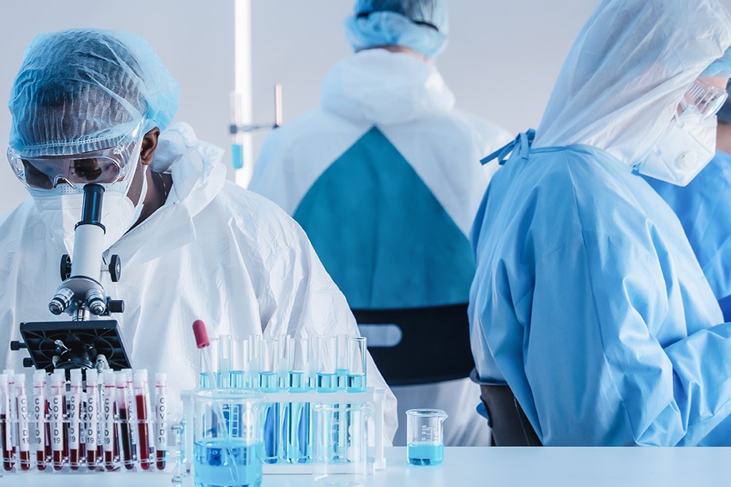 Doctors wearing PPE use lab equipment.