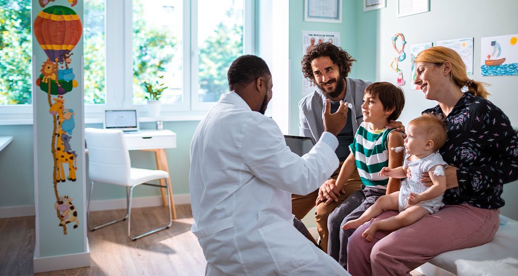 A pediatrician speaks with two young children and their parents