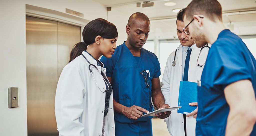 A team of doctors and nurses have a meeting in a hospital hallway