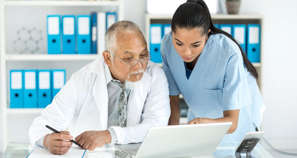 A doctor and a nurse review information on a laptop computer