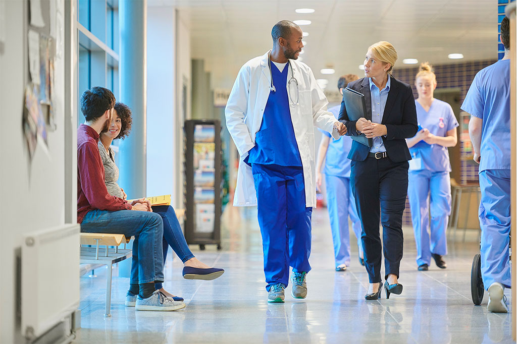 A doctor and administrator speak in a hospital hallway