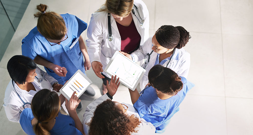 A team of doctors and nurses go over data in a hospital hallway