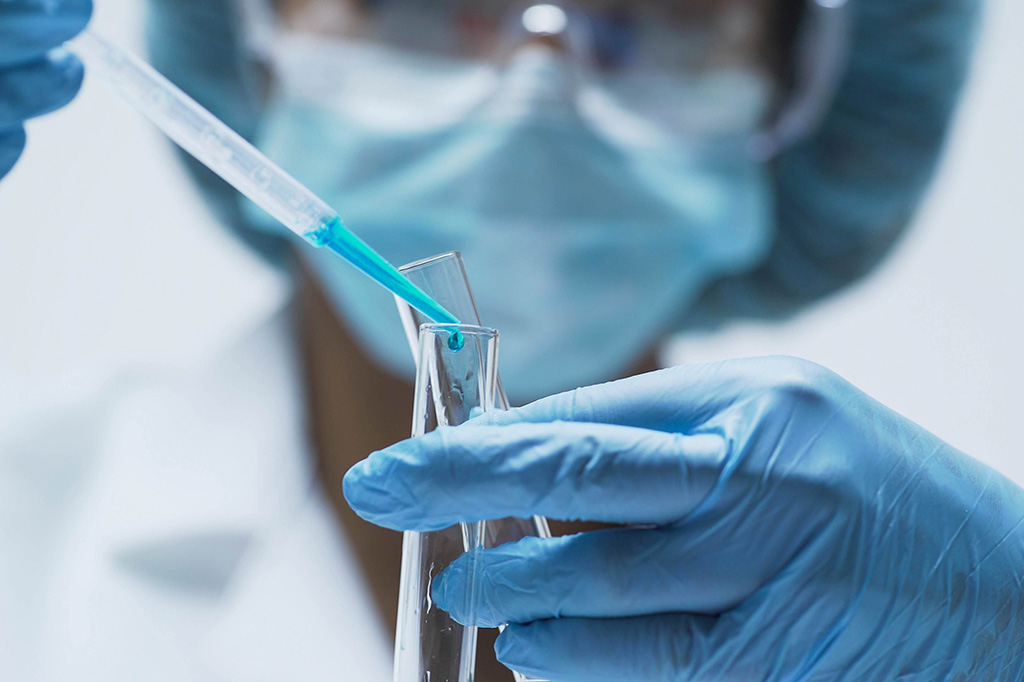 A close up image of a lab worker using a pipette to put liquid into a tube.