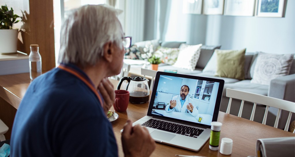 An elderly man speaks with his doctor through a video call.